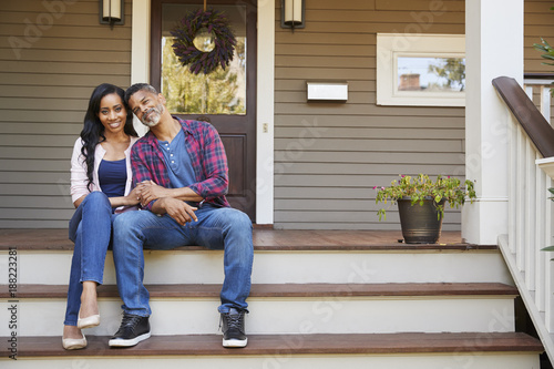 фотографія Couple Sitting On Steps Leading Up To Porch Of Home
