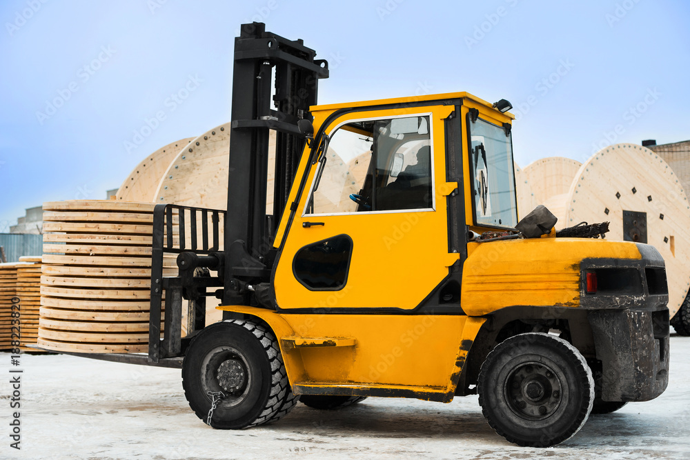 Yellow forklift transports the boards at the industrial area. Woodworking industry