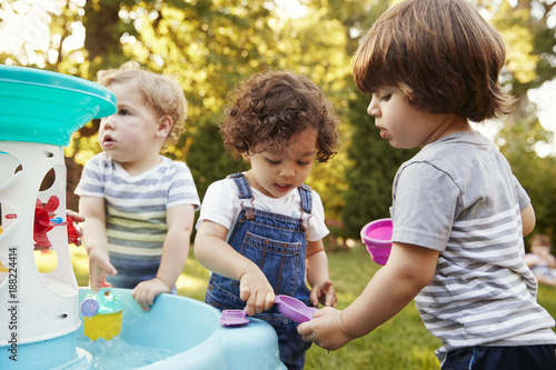 Schilderij op canvas Group Of Young Children Playing With Water Table In Garden