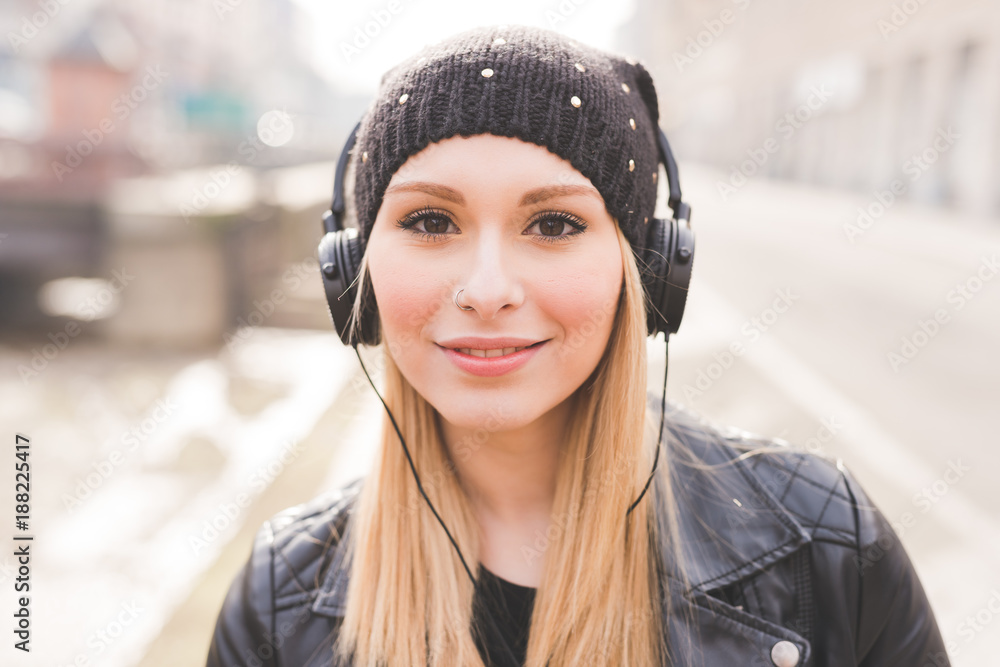 portrait young woman beautiful blonde hair outdoor walking listening music with smart phone hand hold - music, relaxing, technology concept portrait young woman beautiful blonde hair outdoor walking listening music with smart phone hand hold - music, relaxing, technology concept