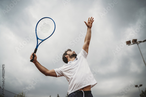 Young man engaged in the tennis service during a match photo