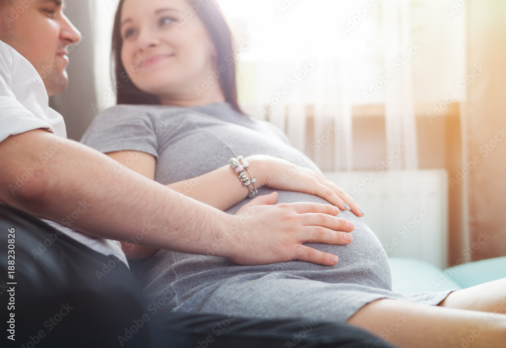 Cheerful pregnant couple relaxing at home and enjoying pregnancy time Cheerful pregnant couple relaxing at home and enjoying pregnancy time