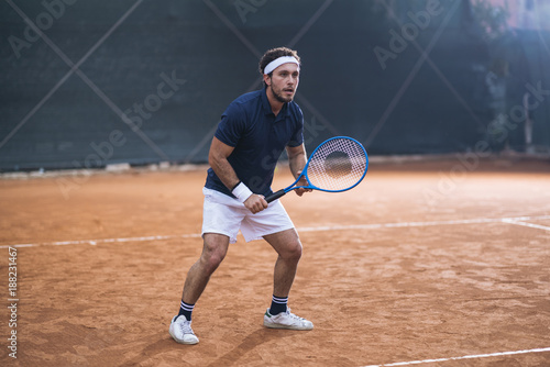 Young man playing tennis on a clay court