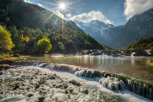White water forest waterfall with mountain range background in sunny day ,autumn season at Blue Moon Valley, Lijiang, Yunnan, China