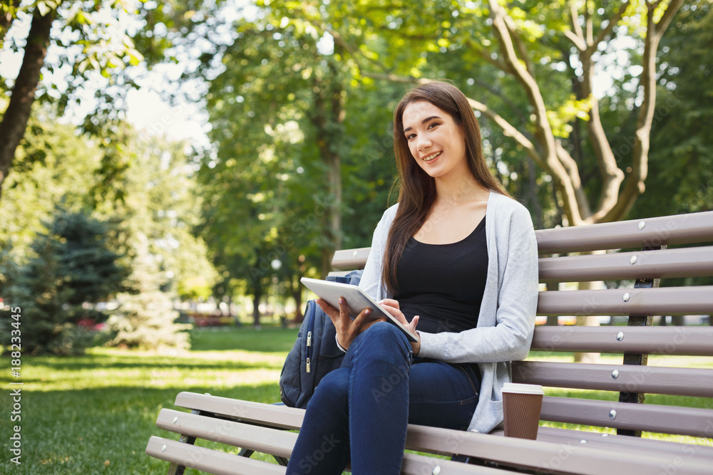 Smiling woman in park using digital tablet Smiling woman in park using digital tablet