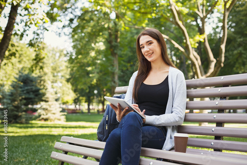 Smiling woman in park using digital tablet