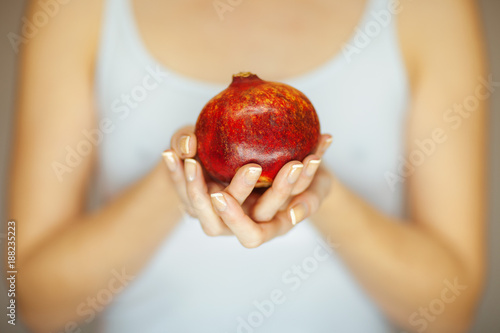 Woman hands holding a pomegranate, sensual studio shot can be used as background photo