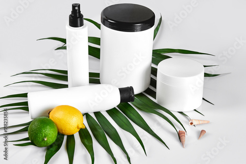 Natural cosmetics for home spa. Top view bottles of cream, shampoo, mask with essential oil, fresh lime fruit, green leaf decor, white background photo