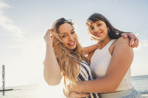 Two young beauty women hug like a couple looking at the camera and look at themselves