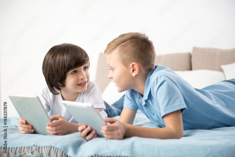 Two kids discussing new game with enthusiasm while playing the tablet at home Two kids discussing new game with enthusiasm while playing the tablet at home