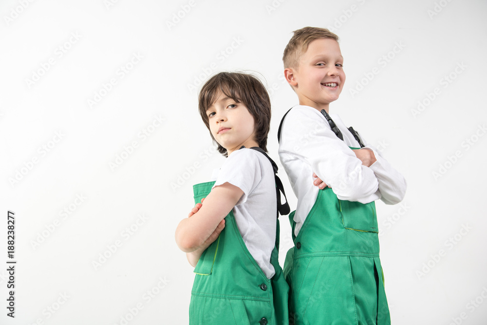 Low angle of young repairmen standing back to back with arms crossed and smiling. Copy space in left side. Isolated on background Low angle of young repairmen standing back to back with arms crossed and smiling. Copy space in left side. Isolated on background