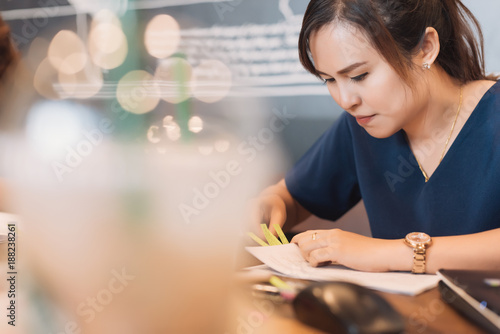 Young Asian woman administrative manager working with financial documentation and financial reports in online database checking in selective focus.
