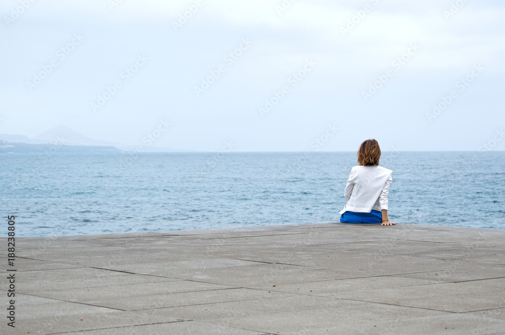 Relaxed and sitting looking at the horizon.