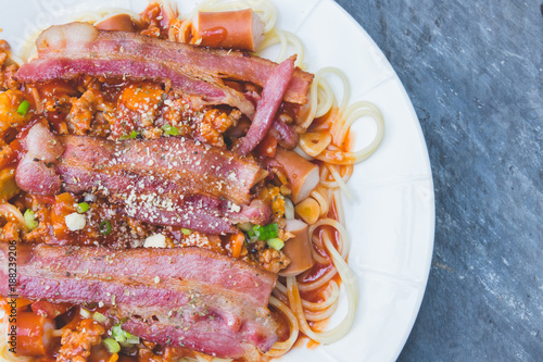 Spaghetti with tomato sauce and suasage with bacon in white dish photo