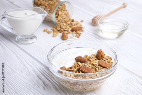 Glass bowl with Greek yogurt and mixed nuts. Healthy sports vegetarian protein rich diet, homemade granola breakfast with milk, honey, almond, cashew, hazelnut, rolled oats. Top front view, background © Evrymmnt