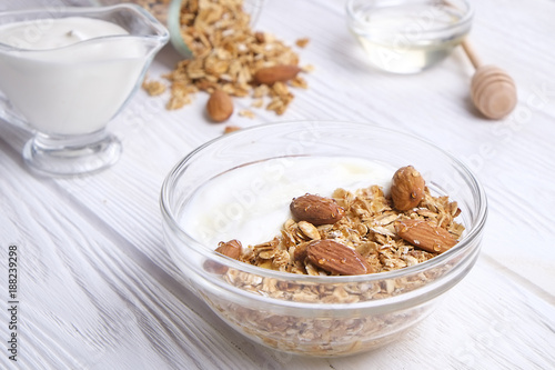 Glass bowl with Greek yogurt and mixed nuts. Healthy sports vegetarian protein rich diet, homemade granola breakfast with milk, honey, almond, cashew, hazelnut, rolled oats. Top front view, background © Evrymmnt
