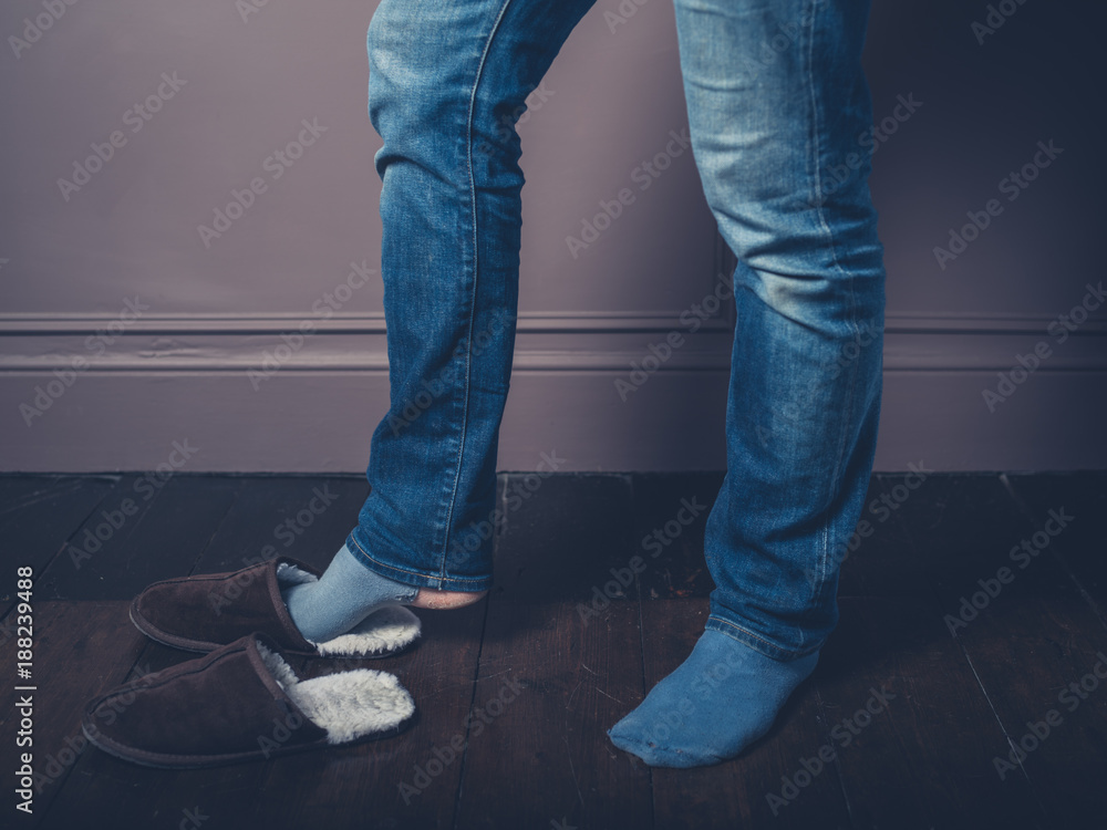 Young man with slippers on wooden floor