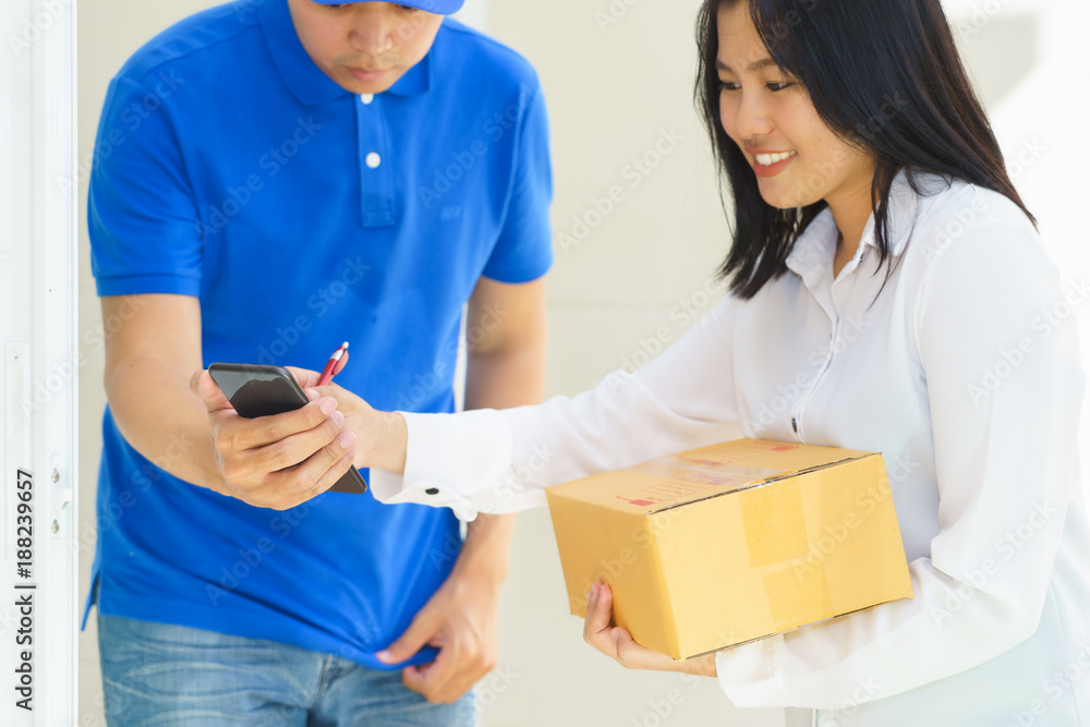 Delivery man pointing on smartphone and woman receiving package and signing on digital mobile phone Delivery man pointing on smartphone and woman receiving package and signing on digital mobile phone
