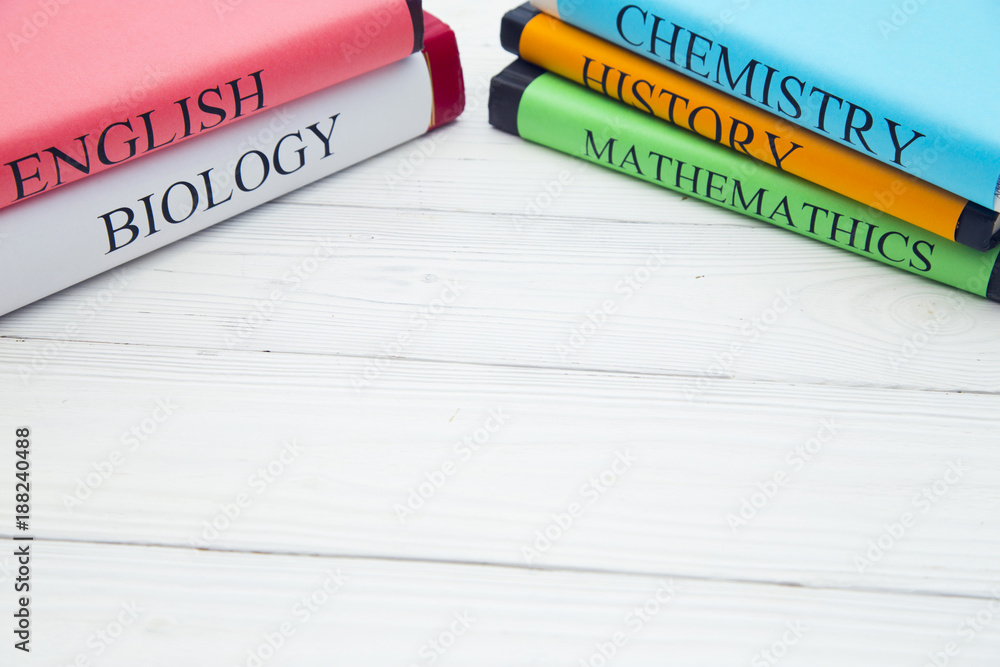 Obraz premium Education concept: school books on different subjects in bright covers on a white wooden table, space for a text or product display