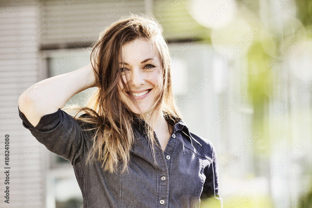 junge Frau mit Piercings und Jeanskleid greift sich lachend ins Haar junge Frau mit Piercings und Jeanskleid greift sich lachend ins Haar
