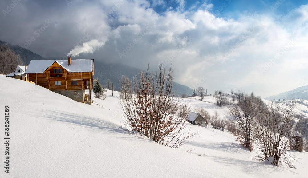 Winter scene, wooden cozy chalet in the mountains with smoke from the chimney