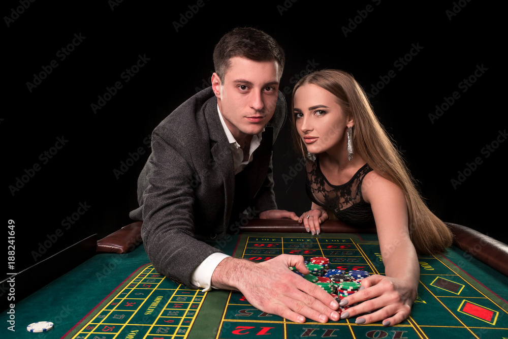 Young beautiful couple takes their winnings at the roulette table at the casino Young beautiful couple takes their winnings at the roulette table at the casino
