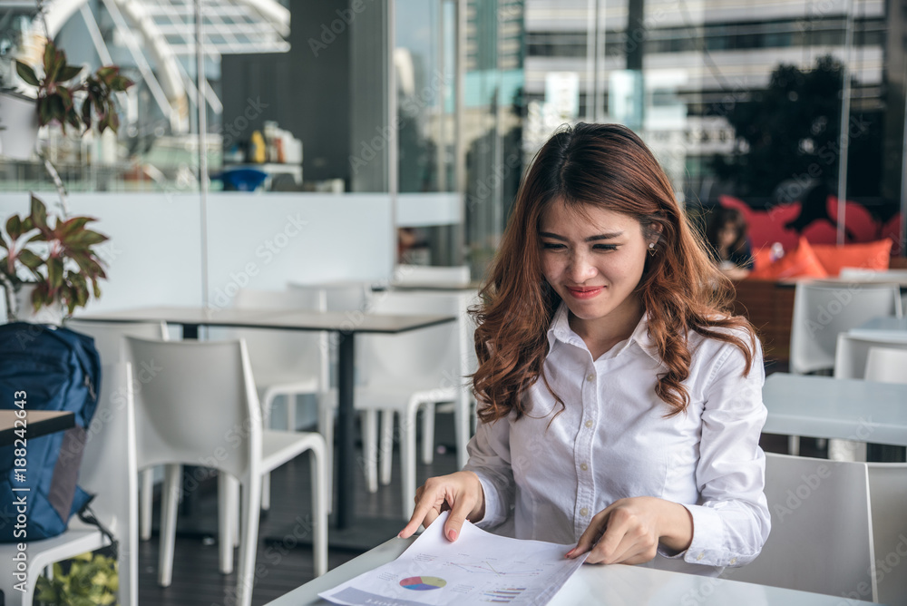 Portraits of beautiful asian woman is holding financ chart document and feeling Portraits of beautiful asian woman is holding financ chart document and feeling