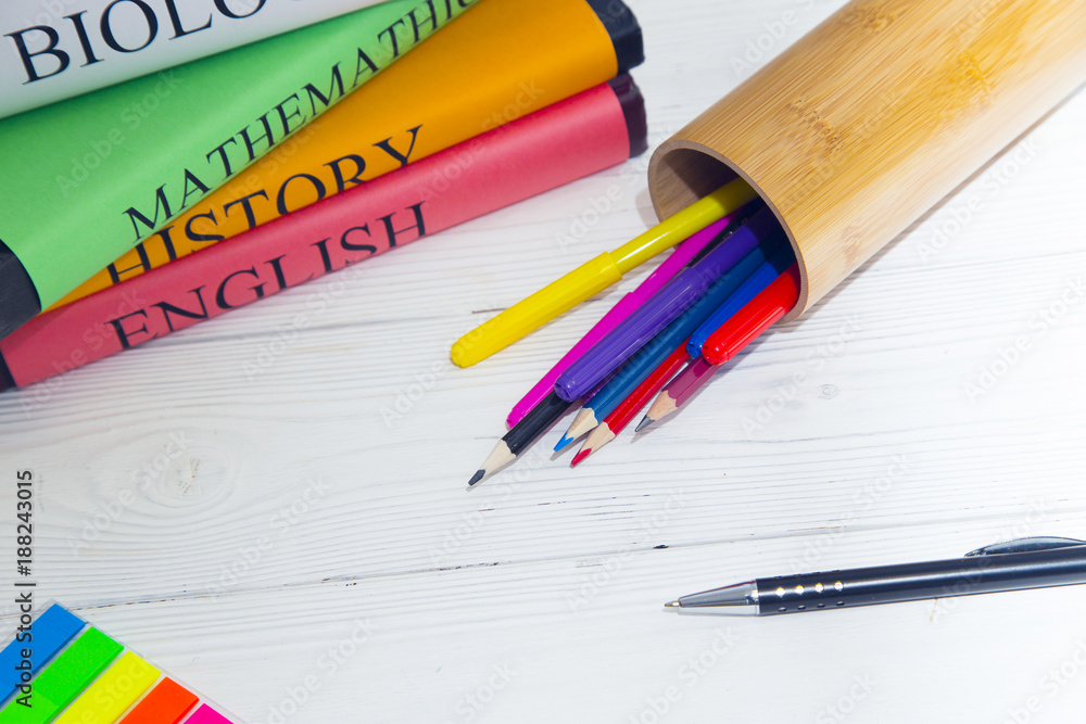 Education concept. Studying for exams. A stack os student's books and a pencilcase with colored pencils and markers on a white wooden table, space for a text or product display Education concept. Studying for exams. A stack os student's books and a pencilcase with colored pencils and markers on a white wooden table, space for a text or product display