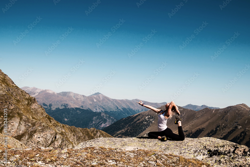 Fototapeta premium Young woman doing yoga pose on the mountain