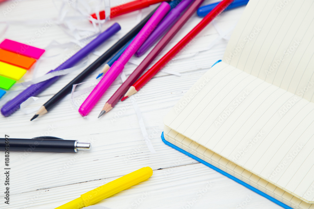 Education and creativity concept. A blank notebook, colored pencils and markers on a white wooden table, space for a text or product display Education and creativity concept. A blank notebook, colored pencils and markers on a white wooden table, space for a text or product display
