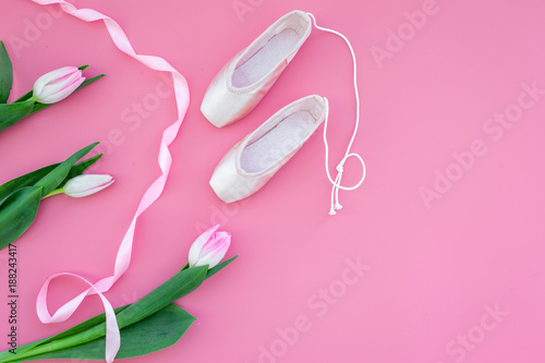 Ballet pointe shoes near spring tulips on pink background top view copy space