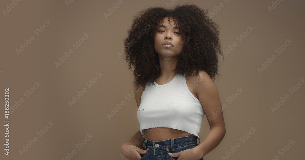 Naklejka premium mixed race black woman portrait with big afro hair, curly hair in beige background