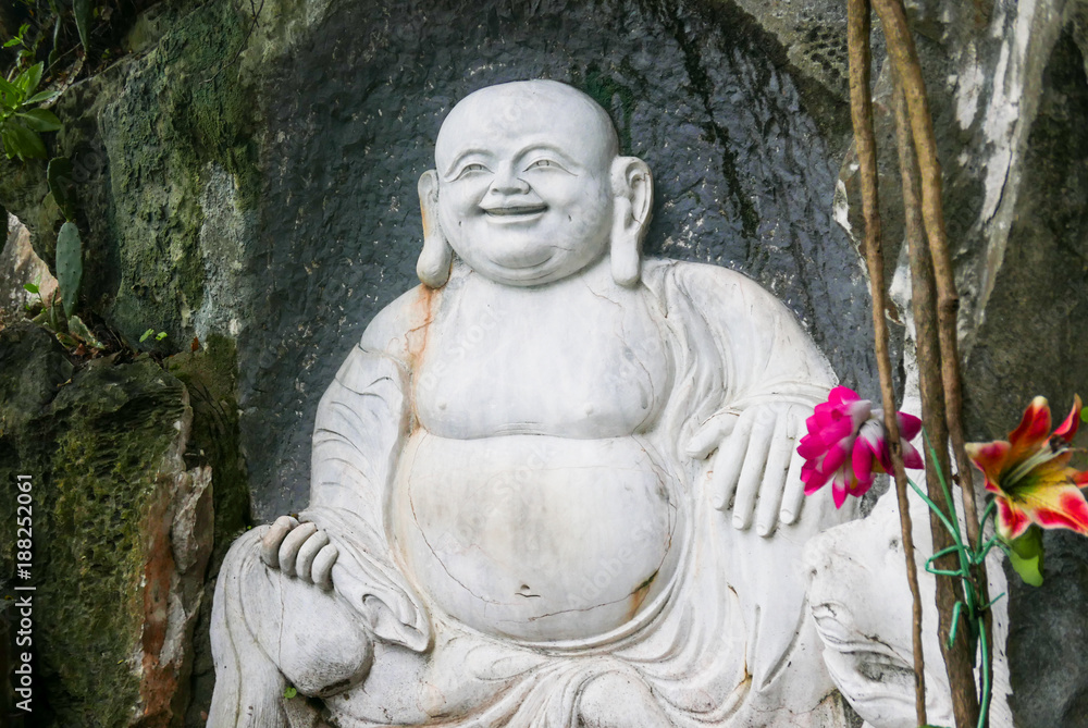 Large carved Buddha with flowers on the side of a mountain in Vietnam Large carved Buddha with flowers on the side of a mountain in Vietnam