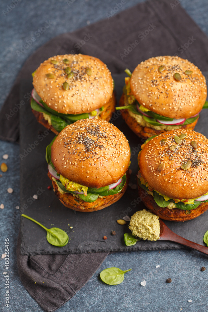 Healthy baked sweet potato burger with whole grain bun, guacamole, vegan mayonnaise and vegetables on a black slate board. Vegetarian food concept, dark background. Healthy baked sweet potato burger with whole grain bun, guacamole, vegan mayonnaise and vegetables on a black slate board. Vegetarian food concept, dark background.