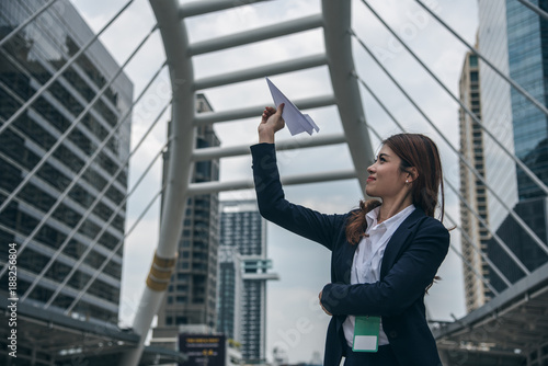Portraits of beautiful asian woman look confidence is standing and holding paper plane. concept of setting business goals.