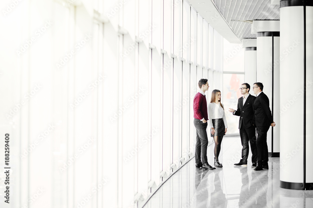 The business people walk in the office hall on the window background The business people walk in the office hall on the window background