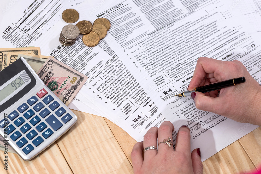 Naklejka premium a woman writes a tax return 1120 w 4 on a wooden table