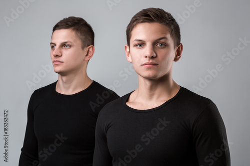 The two twin brother stand on the gray background