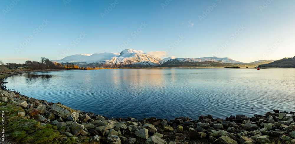 landscape view of scotland and ben nevis near fort william in winter with snow capped mountains and calm blue sky and water