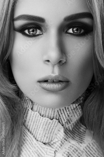 Monochrome closeup beauty art portrait of young beautiful woman blond girl with long straight hair with natural makeup,  newspapers on body. Hairstyle, skincare and cosmetics concept