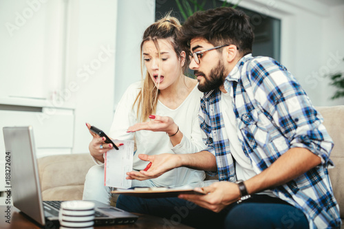 Woman and man doing paperwork together, paying taxes online on notebook pc