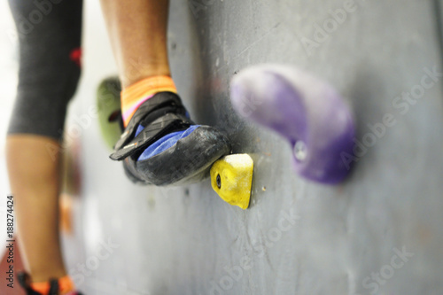 Climbing rocks on climbing wall. Fitness, extreme sport, bouldering, people and healthy lifestyle concept - people exercising at indoor climbing gym. Close-up image
