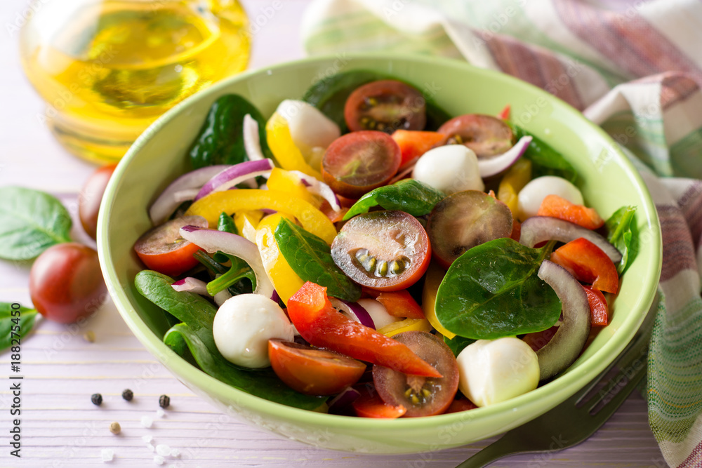 Fresh salad with spinach, bell peppers, tomatoes, red onions and mozzarella on purple wooden background. Fresh salad with spinach, bell peppers, tomatoes, red onions and mozzarella on purple wooden background.