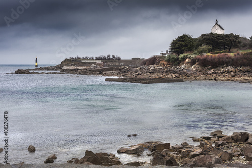 Small chapel and lighthouse with old bunker system at the main entrance of the big harbor of Roscoff, Brittany, France