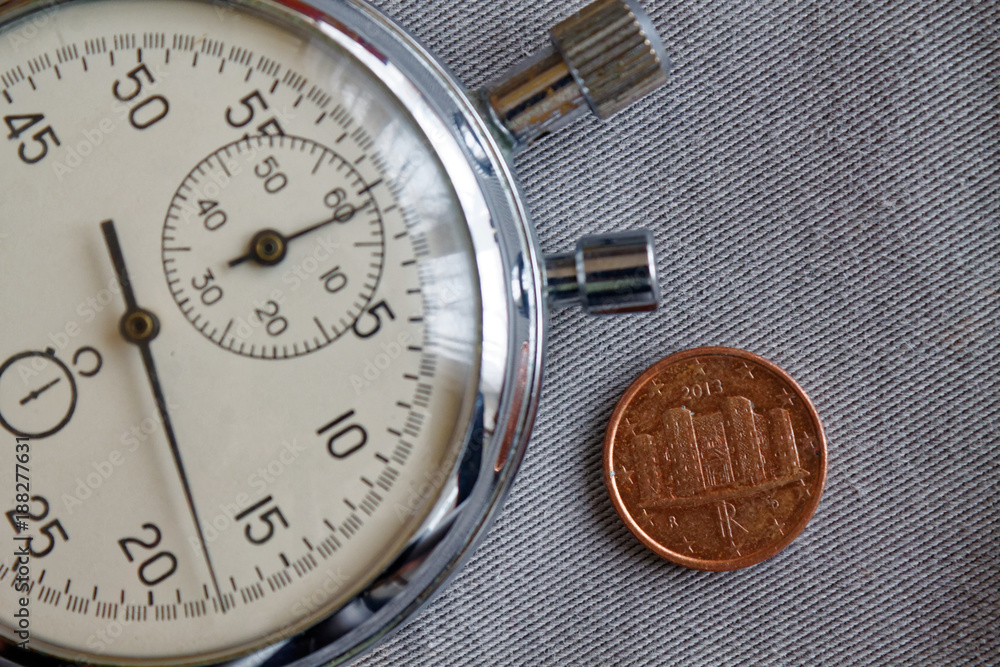 Euro coin with a denomination of 1 euro cent (back side) and stopwatch on gray denim backdrop - business background