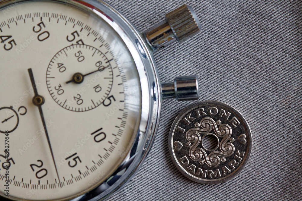 Denmark coin with a denomination of 1 krone (crown) and stopwatch on gray denim backdrop - business background