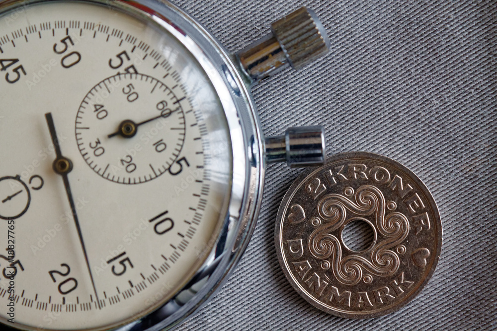 Denmark coin with a denomination of 2 krone (crown) and stopwatch on gray denim backdrop - business background