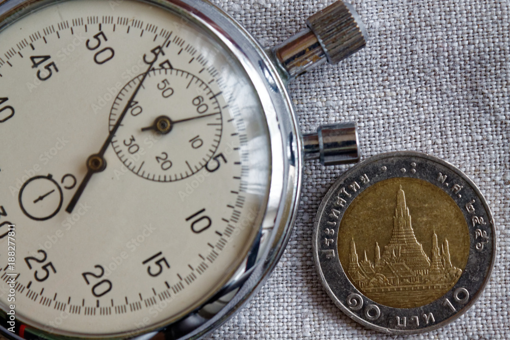 Thai coin with a denomination of 10 baht (back side) and stopwatch on linen backdrop - business background Thai coin with a denomination of 10 baht (back side) and stopwatch on linen backdrop - business background