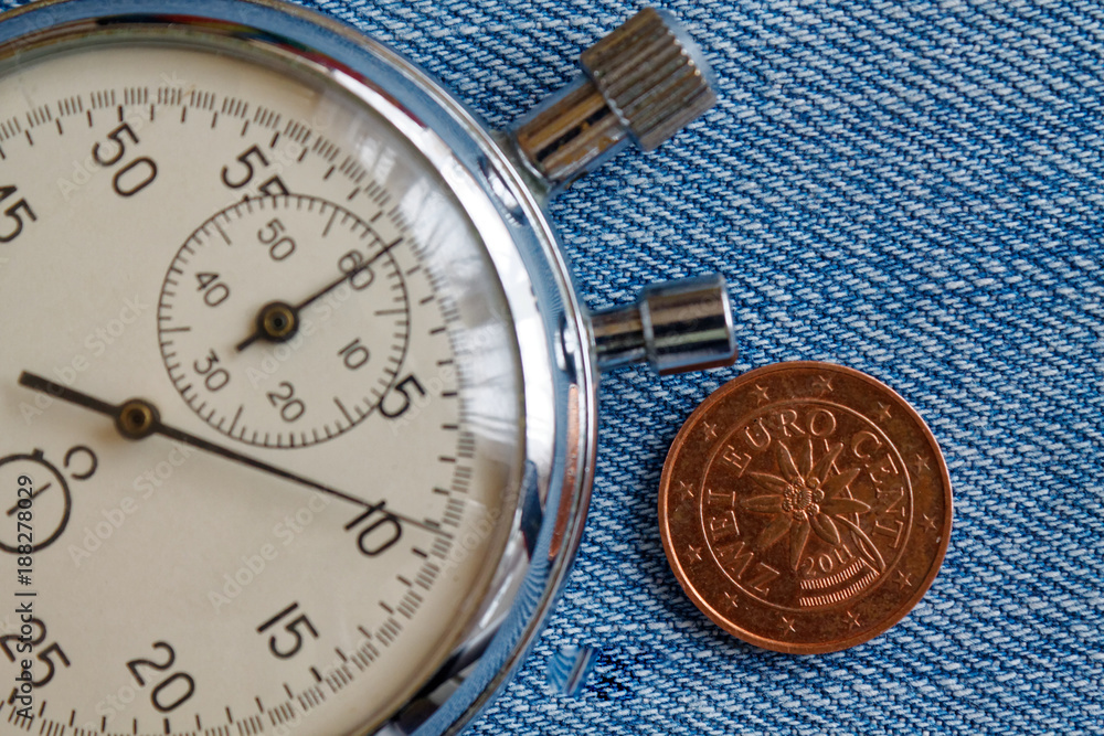 Euro coin with a denomination of two euro cents (back side) and stopwatch on blue denim backdrop - business background