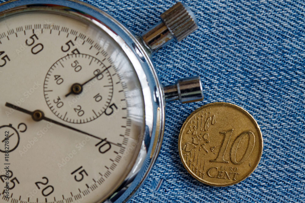 Euro coin with a denomination of 10 euro cents and stopwatch on blue denim backdrop - business background Euro coin with a denomination of 10 euro cents and stopwatch on blue denim backdrop - business background